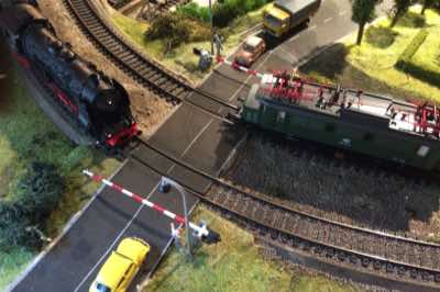 BR 18 steam locomotive and BR 144 electric locomotive passing each other at the Poggendorf railroad crossing.