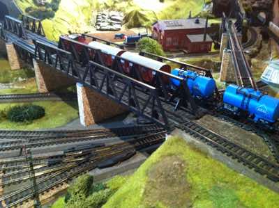 A freight train with Gmhs 53 Box goods wagons and Aral tank wagons pulled by a BR212 diesel locomotive crossing the Poggenbach bridges.